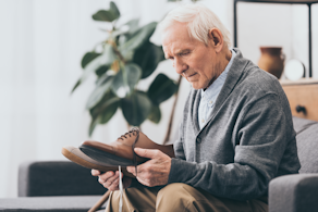 Life Assure Senior Man Holding shoes While Sitting On Sofa Blog